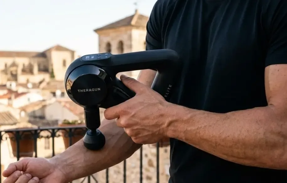 Pistola de masaje Theragun Elite negra brillante con su característico diseño triangular patentado siendo sujetada por una mano firme