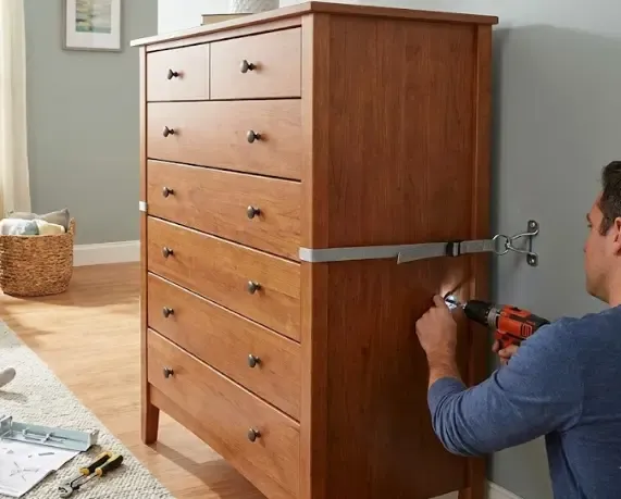 Ilustración de seguridad mostrando el riesgo de vuelco y el anclaje correcto a la pared